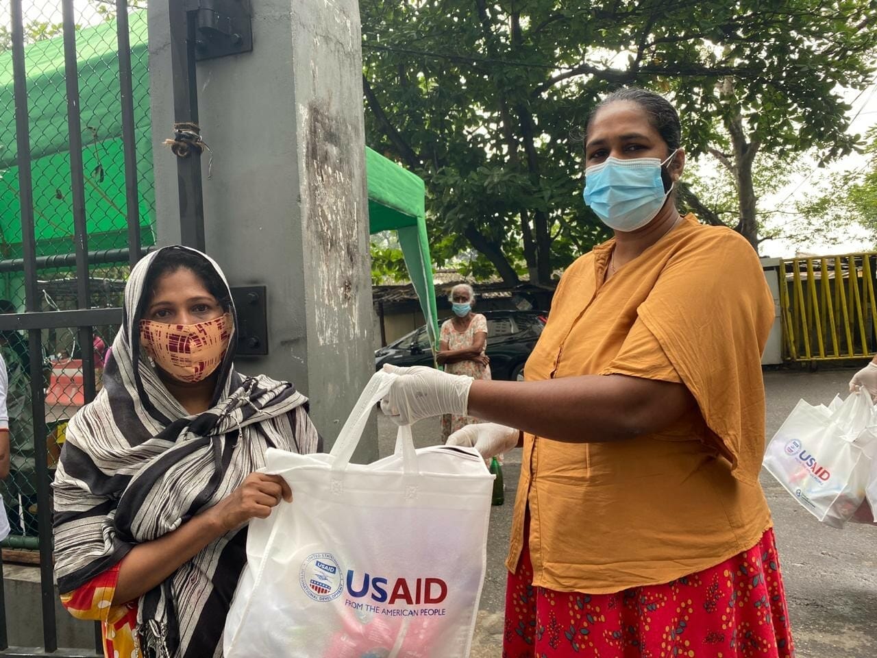 A CMC official hands over a USAID-donated hygiene pack to a resident at Modara flats