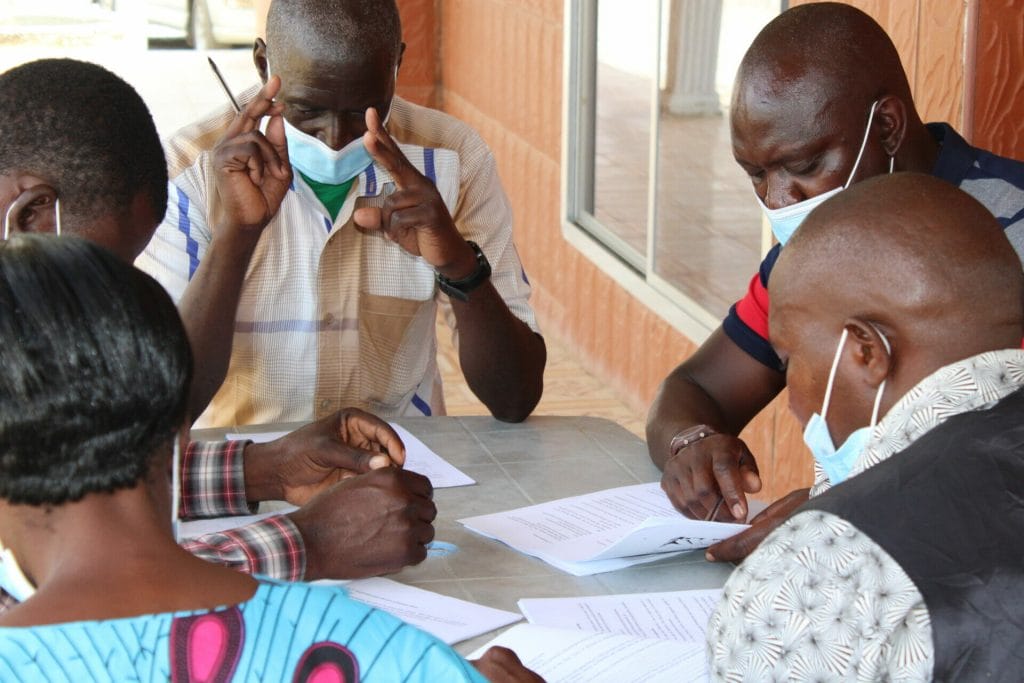 Business plan development group discussion Zambian farmers seated around the table participating in a business training designed to increase climate resilience and productivity.