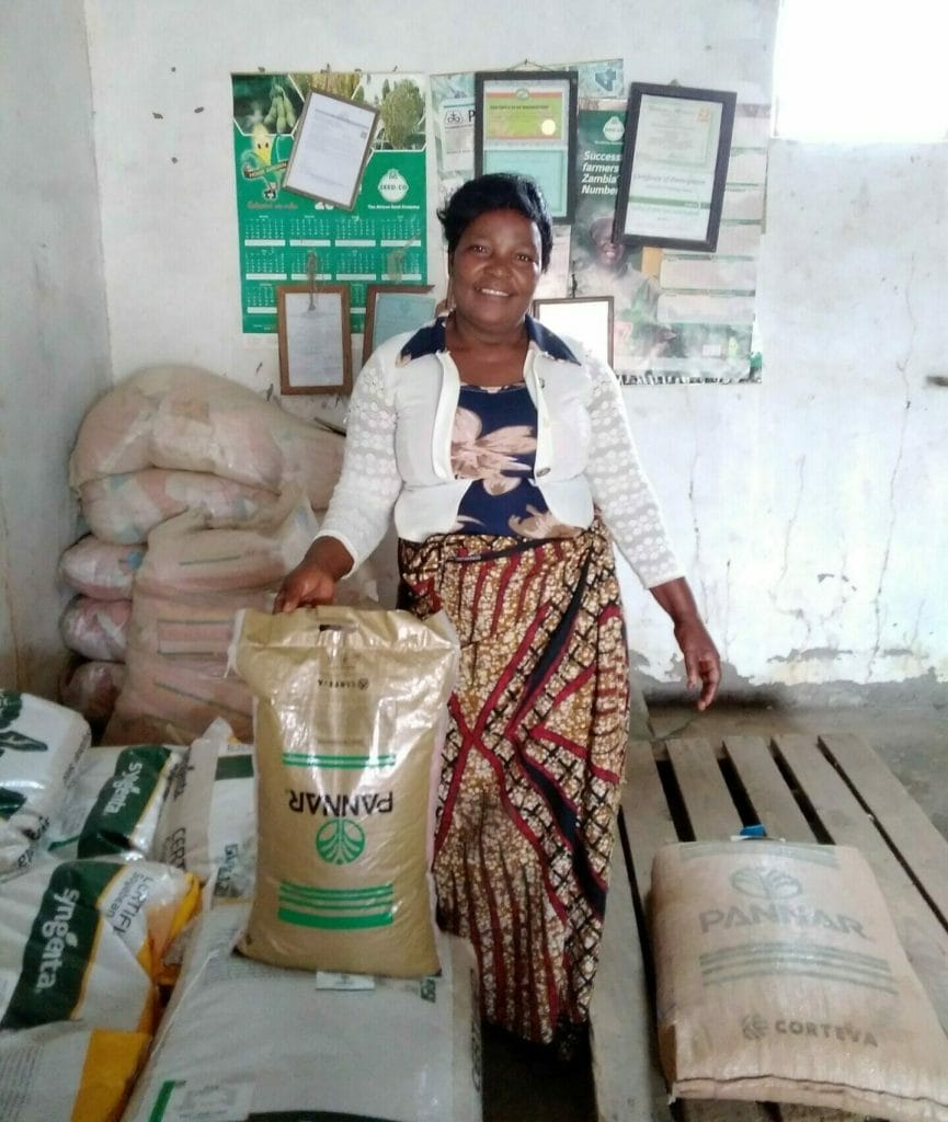 Zambian farmer, Christine holds up one bag of Pannar hybrid seeds, which will help with climate resilience, in her storehouse.